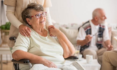 Happy senior lady sitting at wheelchair in nursing home for elderly